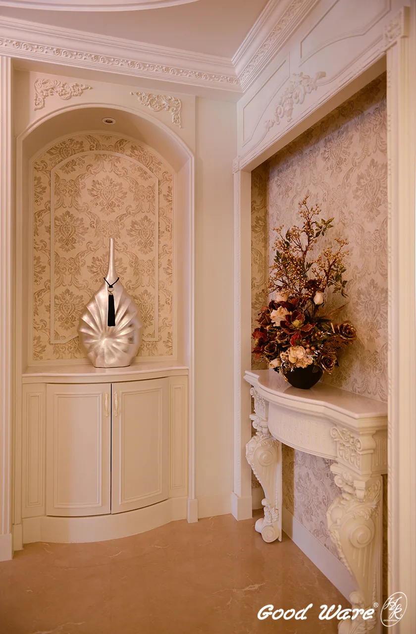 廊道盡頭以門窗框線板修飾，素花色壁紙提升空間典雅、靜謐氛圍，以壁爐柱做置物平台，緊鄰另一側的櫃體則與通往客廳的拱門相呼應。